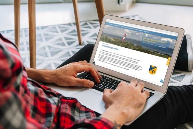 Ein Mann betrachtet die Homepage des Amtes Geltinger Bucht auf einem Laptop